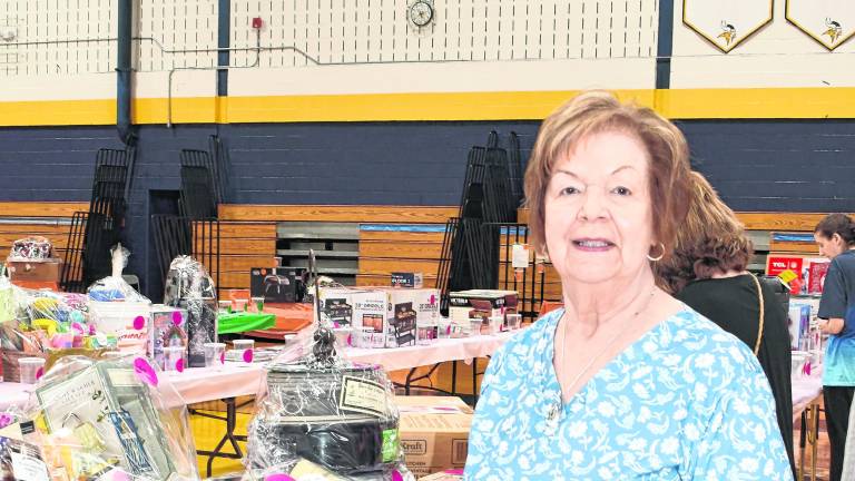 <b>Joann Lisa of Vernon stands in front of a table.</b>